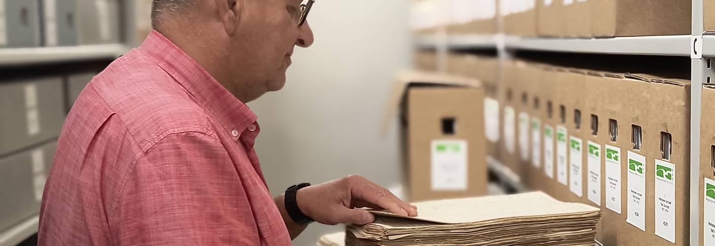 Man bekijkt oude akten in een archiefruimte