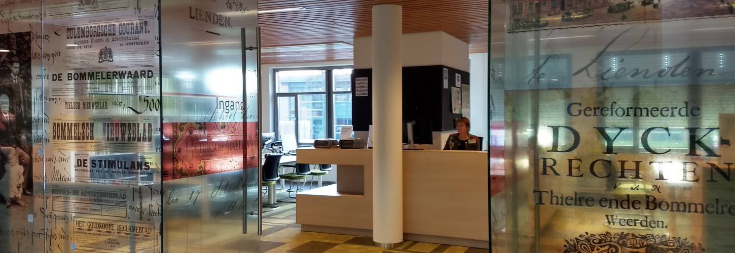 glazen wand studiezaal met open deur en iemand achter de balie in de studiezaal