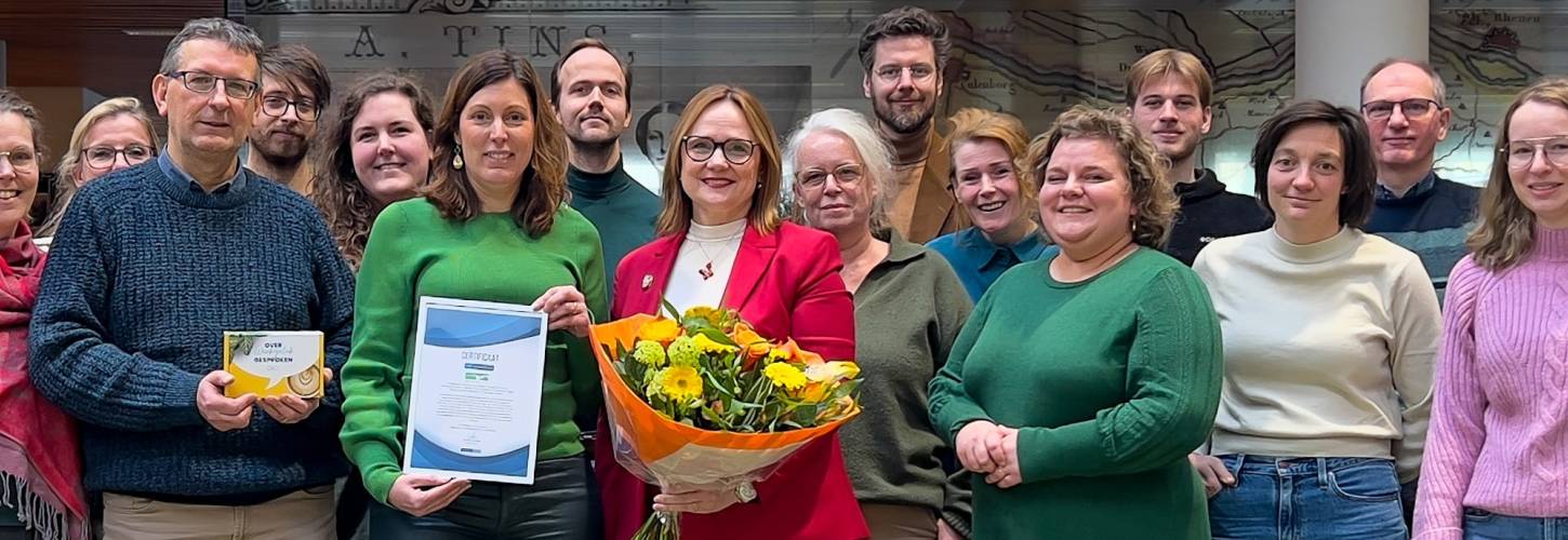 medewerkers van het RAR poseren met bloemen en het certificaat Topwerkgever van MonitorGroep