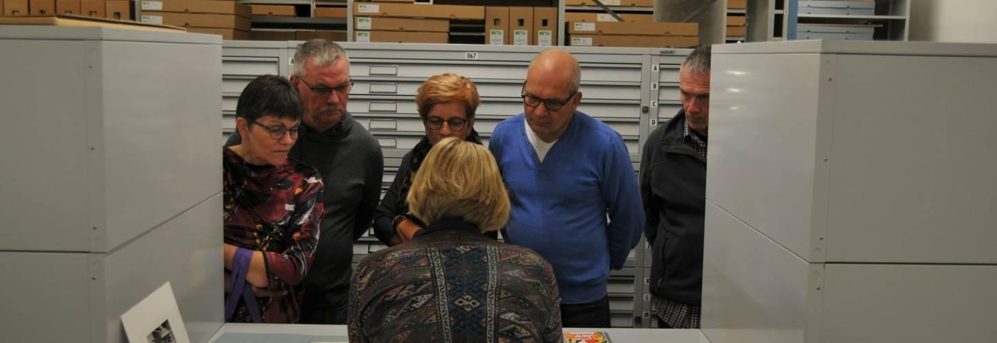 Mensen krijgen uitleg in een depot over archiefstukkenv an het RAR