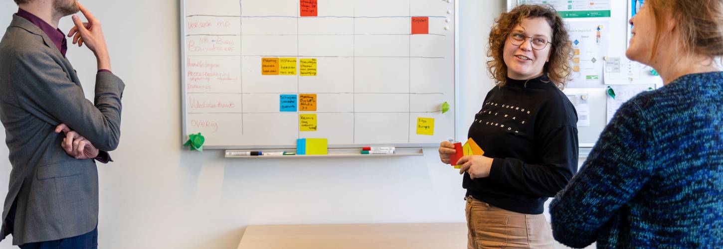 Collega's Léon Jonna en Djoke van de cluster digitale ontwikkelingen in overleg bij een white board met gekleurde post-it briefjes
