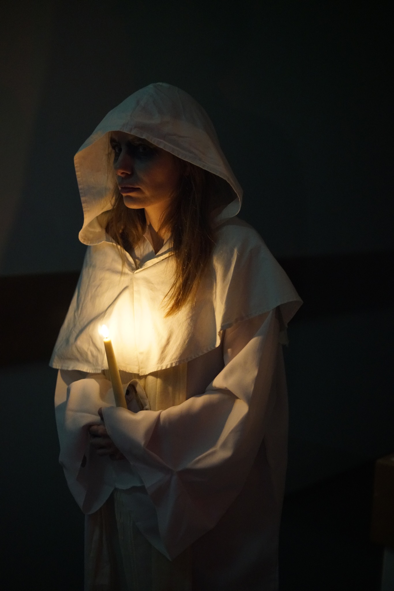 vrouw in het wit gekleed met een kaars