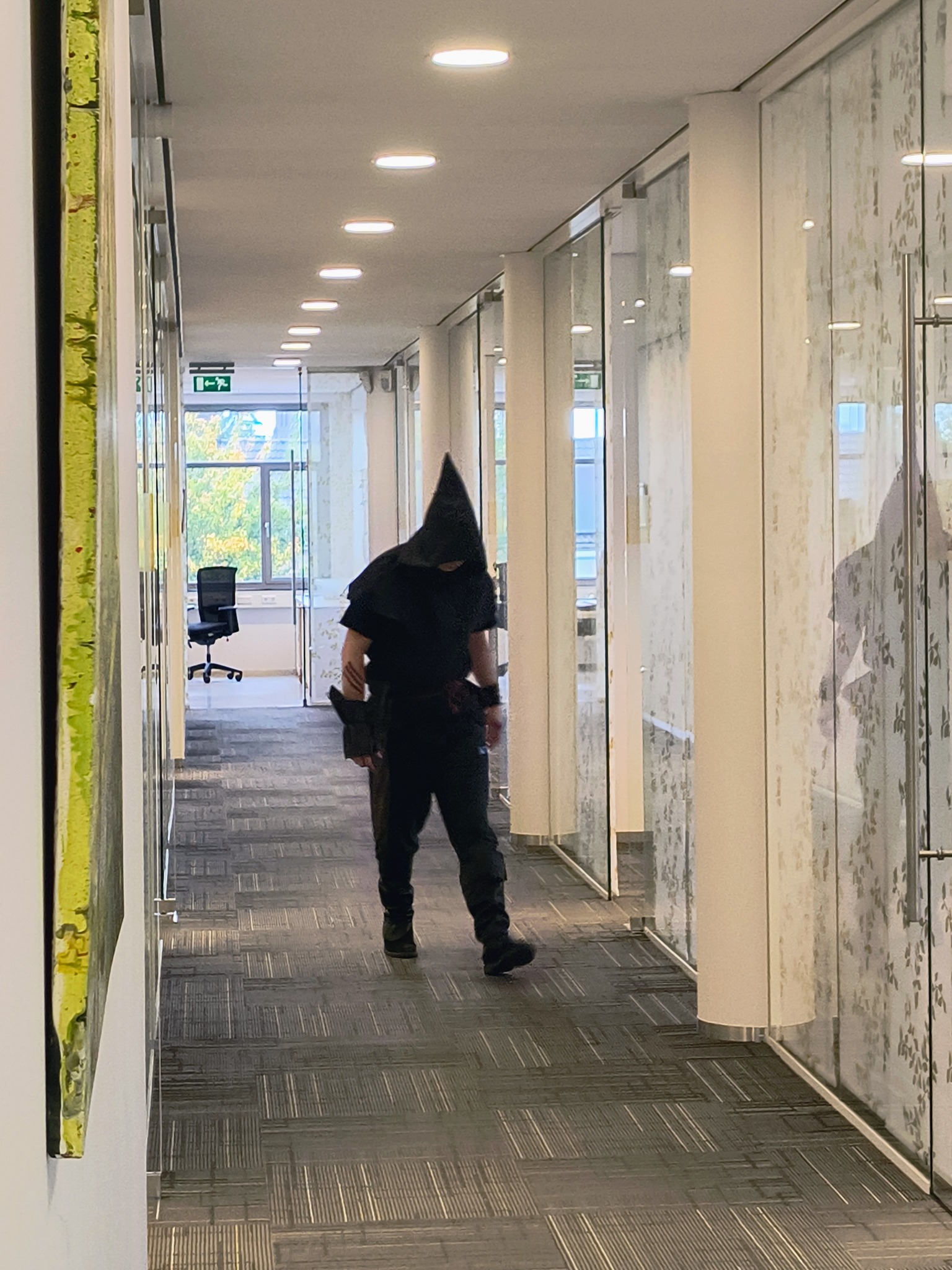 man verkleed als beul loopt door een kantoorgang
